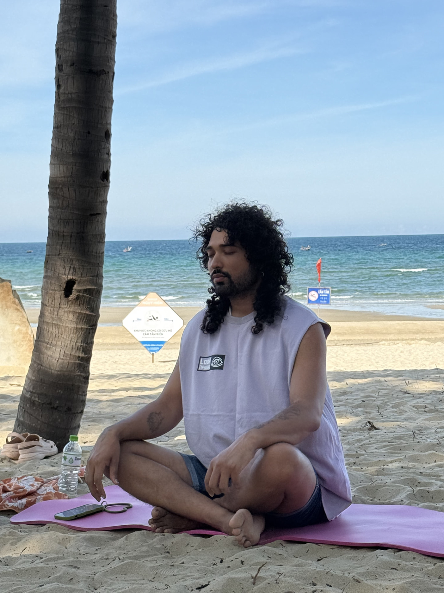 Eklavya meditating on a beach beneath a palm tree